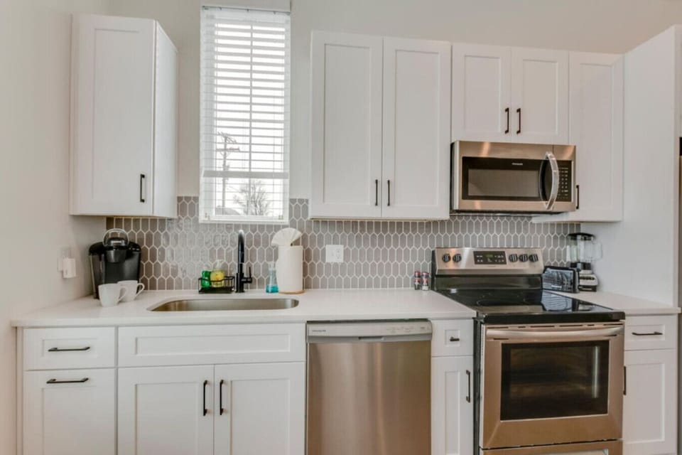 A clean kitchen with stainless appliances, subway tile backsplash, and bar seating makes cooking a pleasure.