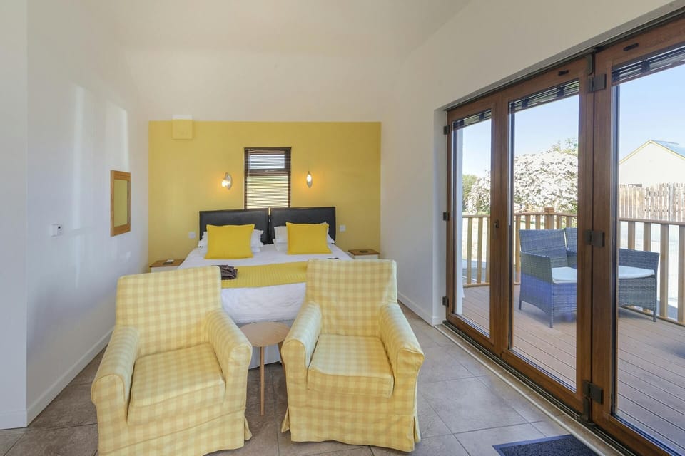 Bedroom area with bed, two armchairs and patio doors