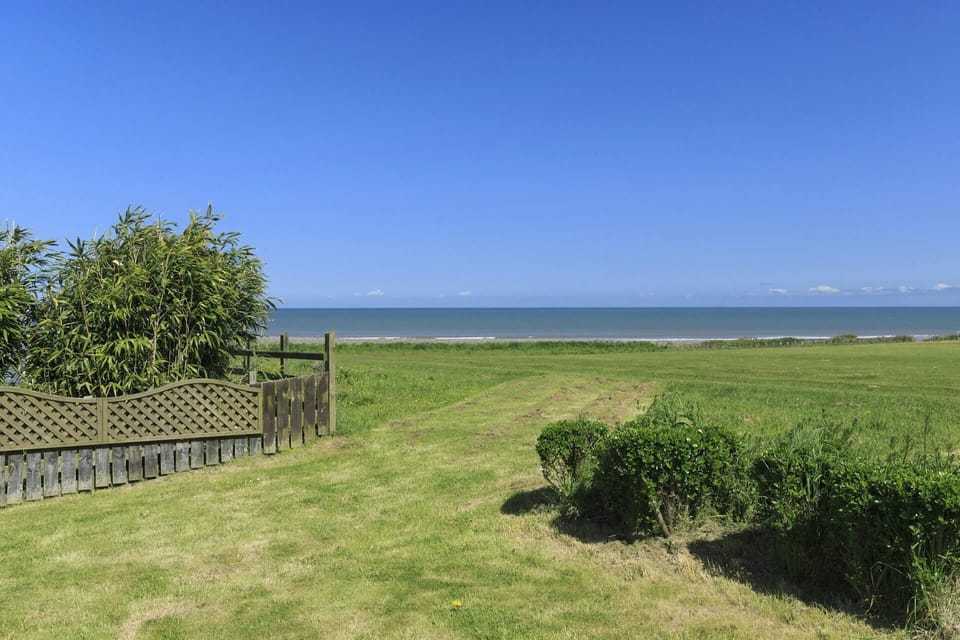 Lawn and fence in grounds at Swn y Mor with view over fields to the sea