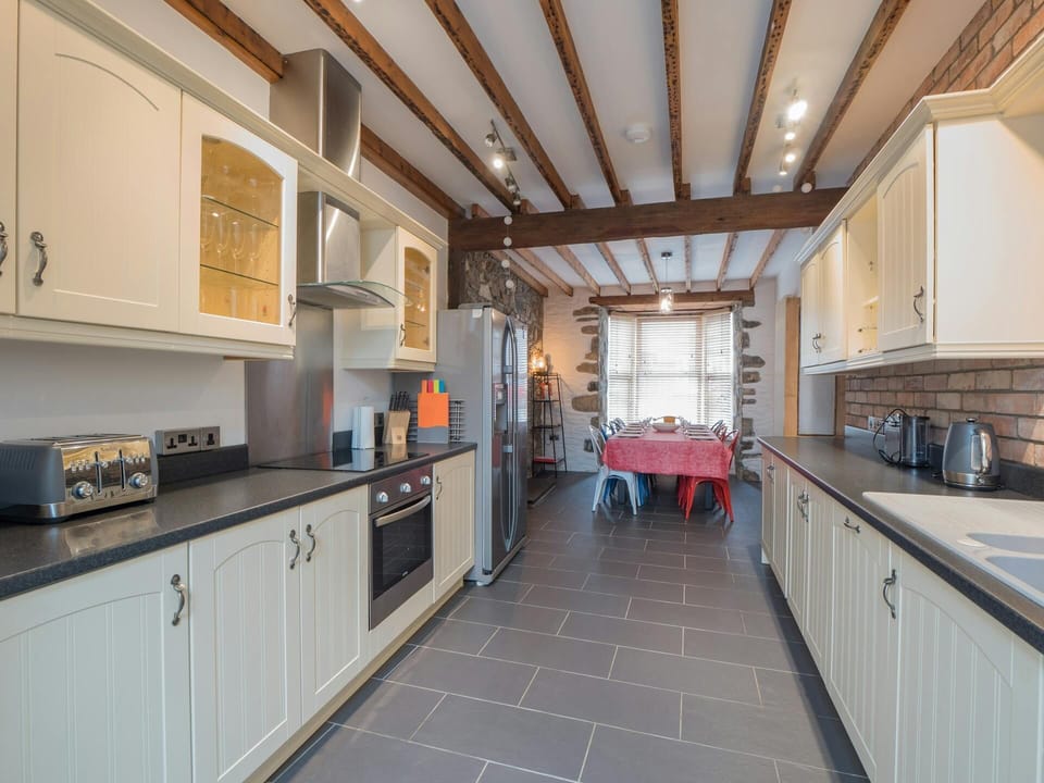 Long kitchen with cabinets each side, oven, hob, toaster and kettle