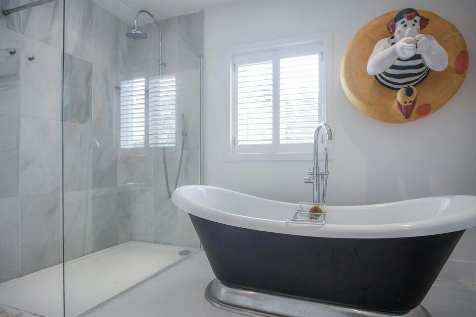 Extra large walk in shower. Large roll top bath. Artwork on wall. Plantation blinds on the window