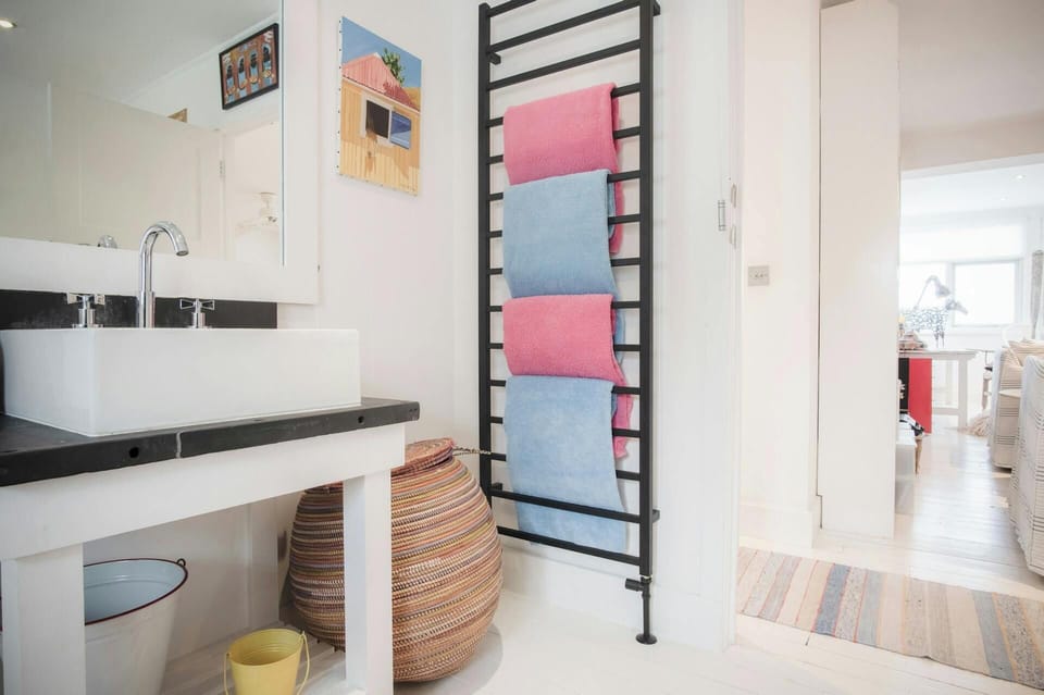 Shower room with tall heated towel rail and towels, wash basin and mirror