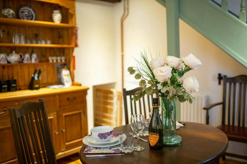 Dining table laid for dinner with bottle of wine and vase of flowers