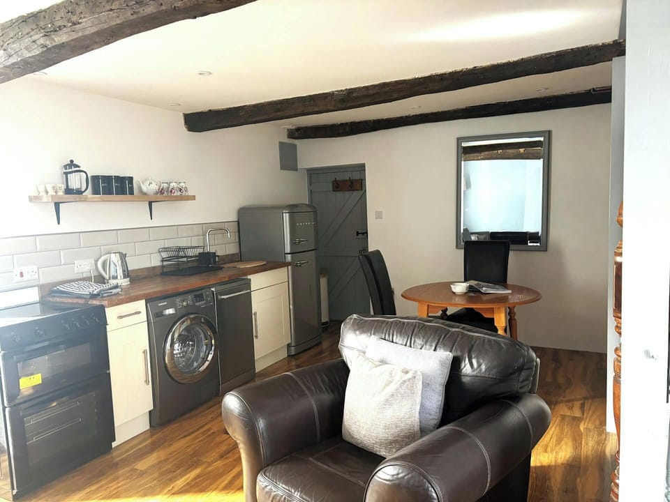 Open-plan room with kitchen units, washing machine, fridge and dining table