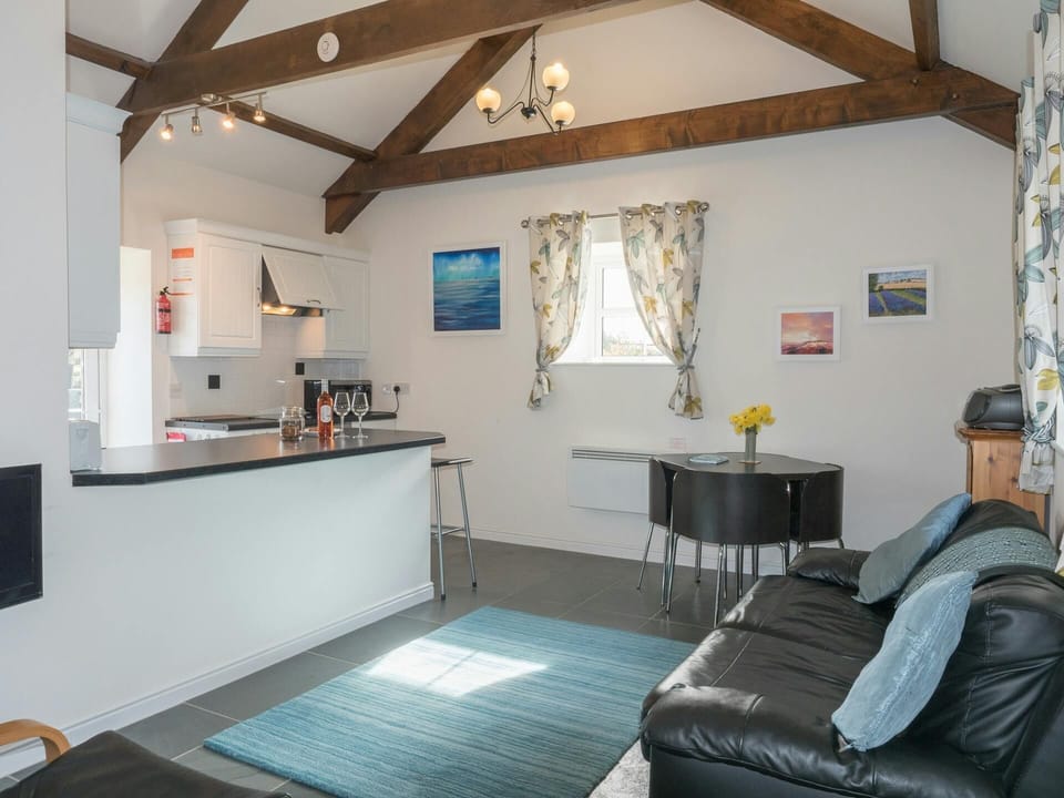 Living area at The Old Forge, sofa, table and chairs, kitchen, vaulted ceiling