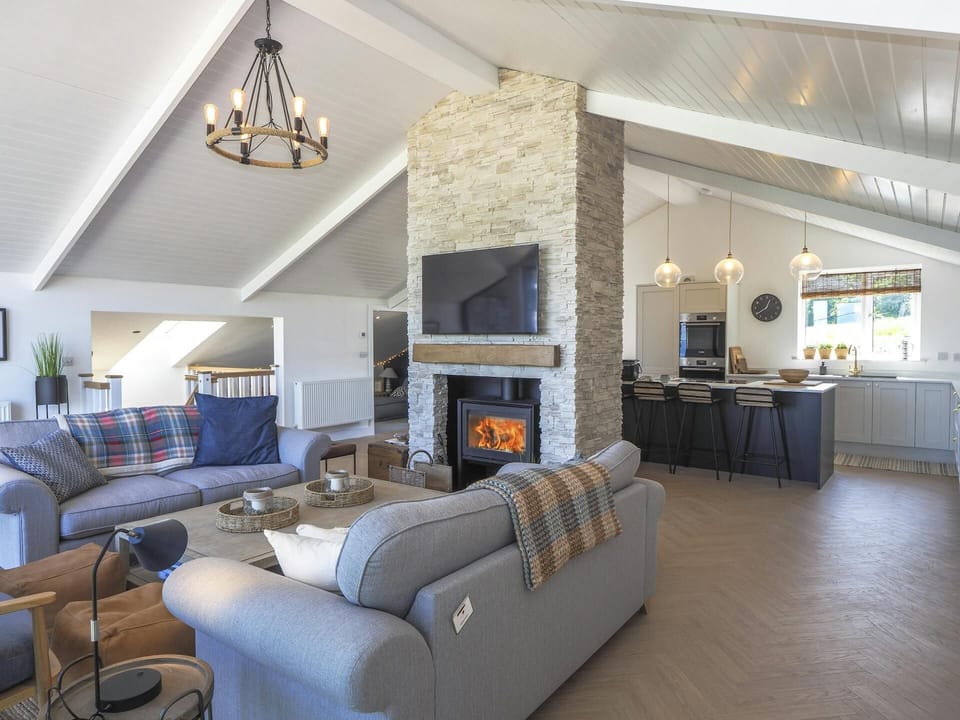 Lounge room with sofas and a Tv on the wall behind the kitchen.