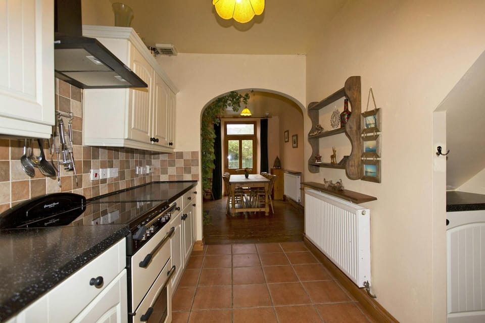 Fitted kitchen with cooker; leading to dining area with table and seven chairs