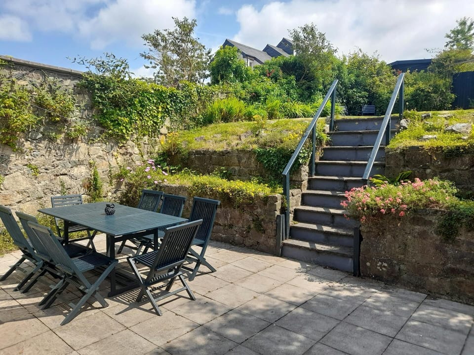Patio area; table with eight chairs and steps leading to the garden