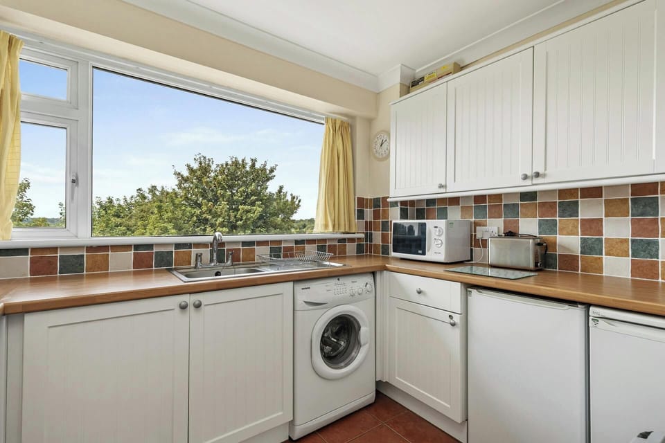 Kitchen interior with sink, washing machine, and fridge, and a tiled backsplash in blue and orange