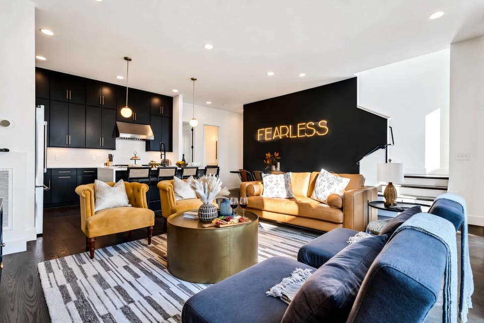 Open-concept living and kitchen with a statement neon sign and enough seating to keep everyone together for movie nights and downtime