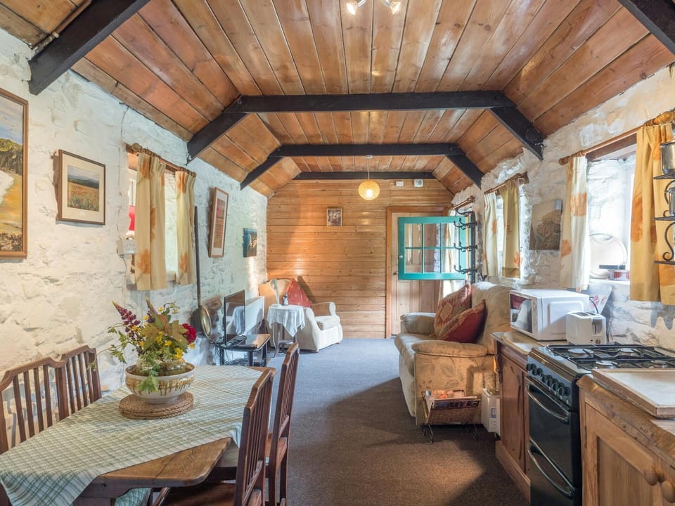 Living area with dining table and four chairs, cooker, microwave, toaster and seating area
