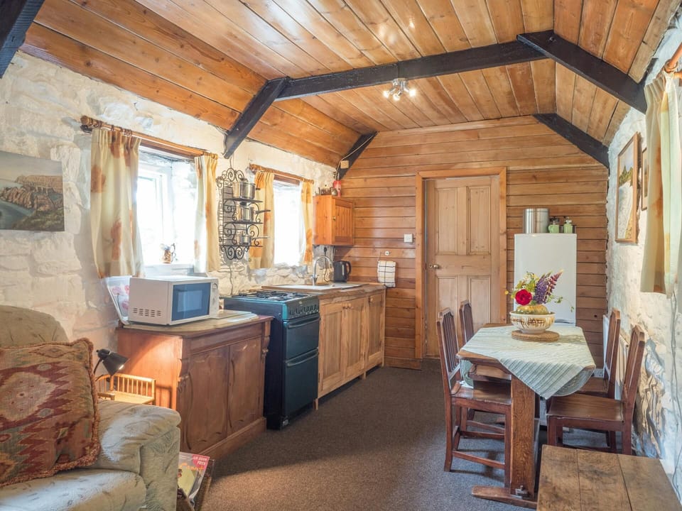 Kitchen with wood beamed ceiling and two windows; cooker, microwave, kettle, fridge/freezer; dining table with four chairs