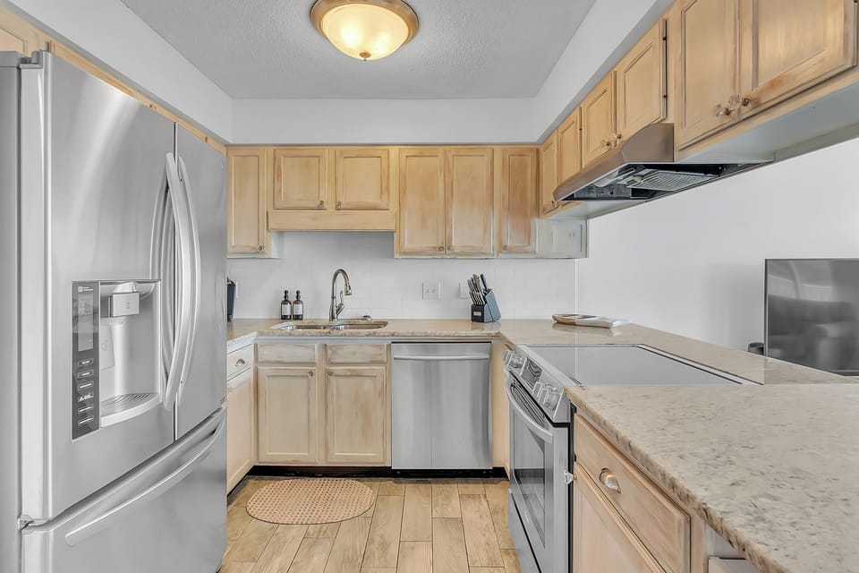 Your fully equipped kitchen awaits with stainless steel appliances, granite counters, and warm wood cabinets perfect for preparing memorable meals.