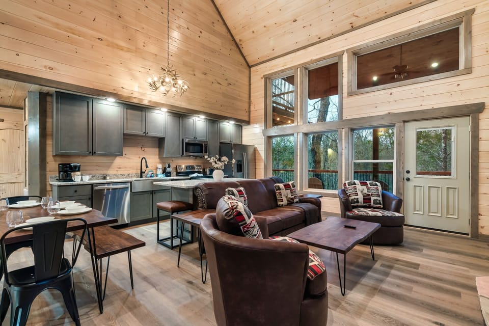 Open concept living room with large screen TV, sleeper sofa, & swivel chairs
