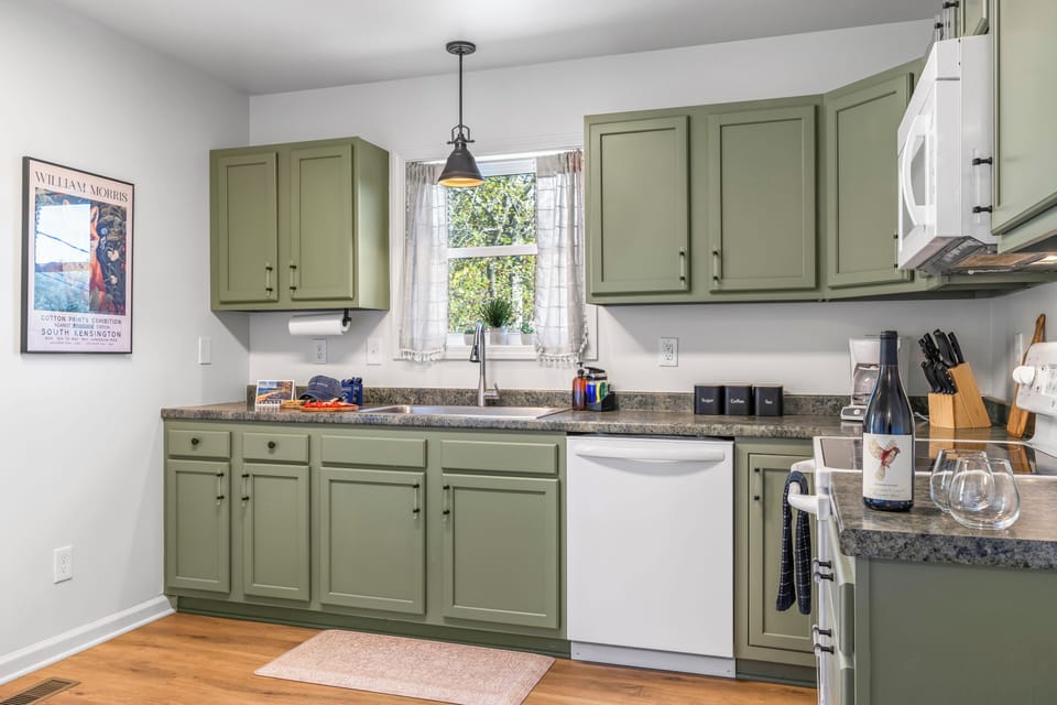 Fully equipped kitchen with stove, dishwasher, and bold matcha cabinets.