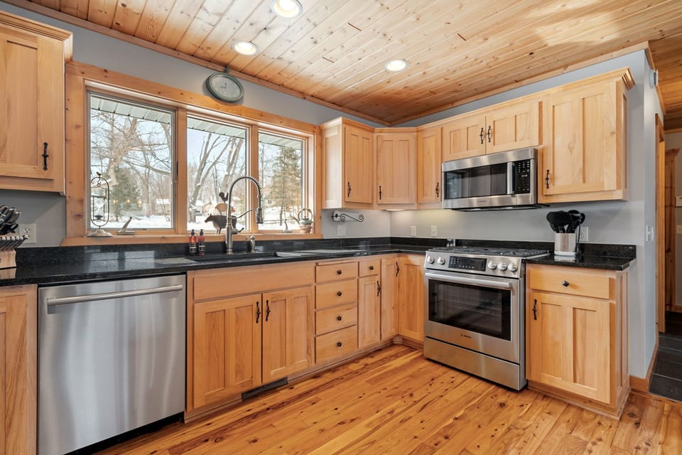 Prepare your favorite meals in this stunning rustic kitchen featuring warm wood cabinets, granite countertops, and modern stainless steel appliances.