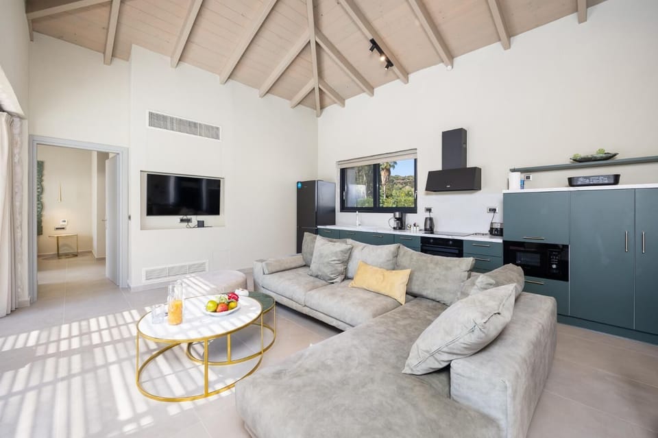 Open-plan living room with sofa, dining area, kitchen, A/C, WiFi internet, and satellite TV