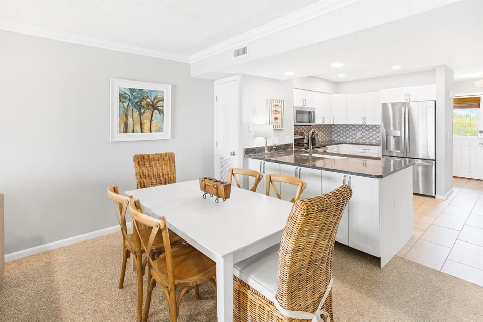 Gather around your spacious dining table with coastal charm, where wicker chairs invite leisurely meals beside your fully equipped modern kitchen.