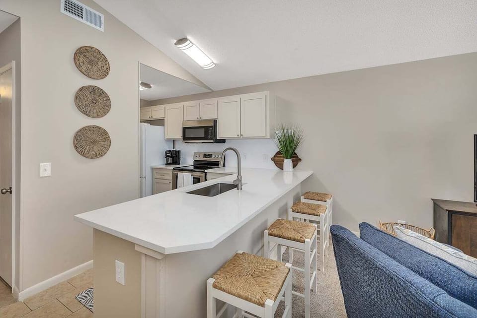 White kitchen with bar seating and stainless appliances