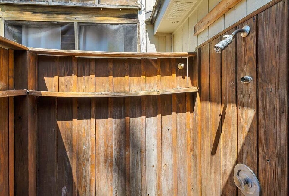Rustic outdoor wooden shower enclosure with showerhead