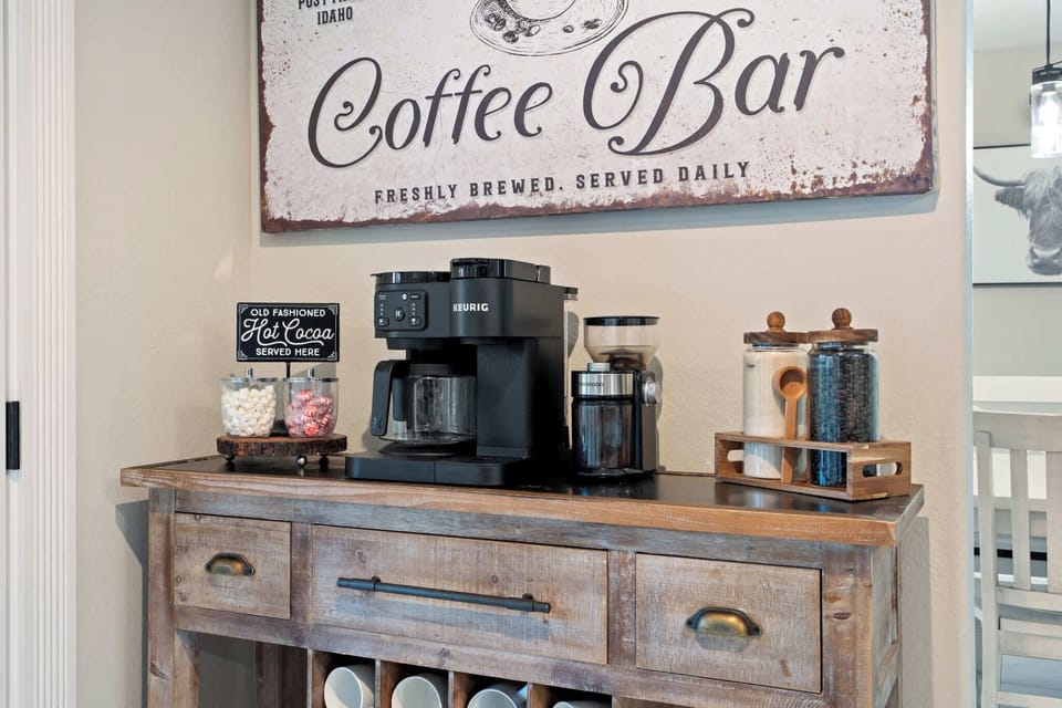 Dedicated coffee station with Keurig machine, ground coffee options, mugs, and morning essentials ready to go.