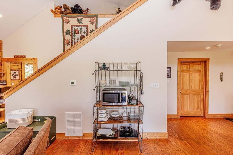 Staircase landing area with shelving, wood flooring, and access to additional rooms. The open design connects the main living area to the upper level.