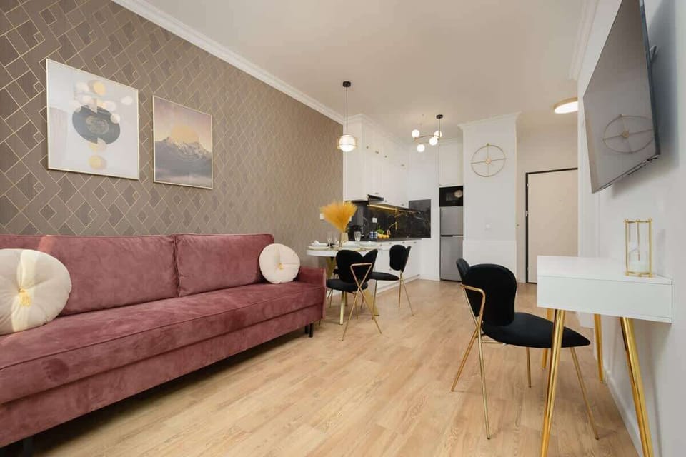 Another view of the living room, highlighting the plush pink sofa, stylish artwork, and warm-toned decor.

