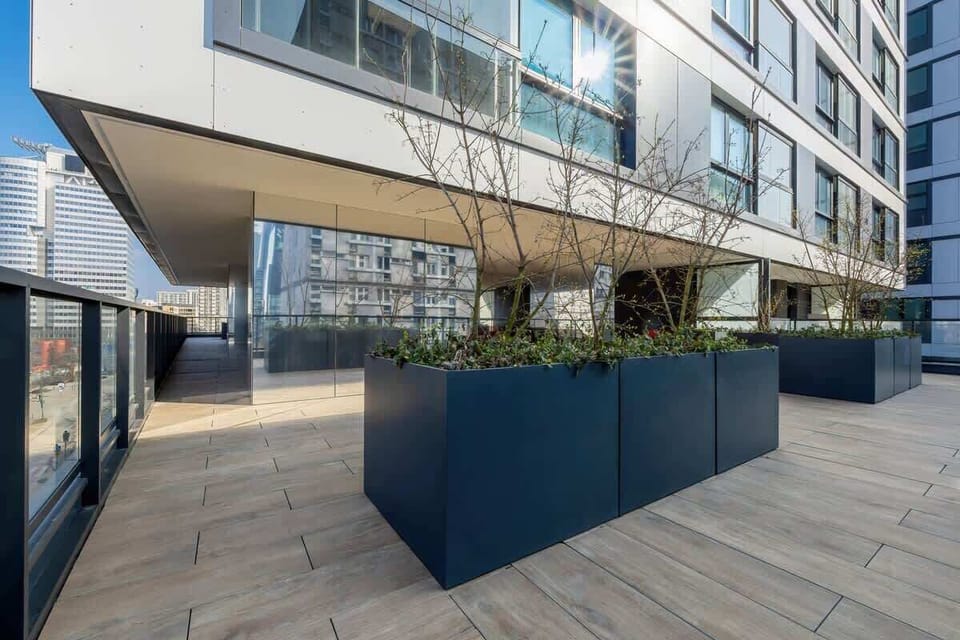 Another view of the balcony, emphasizing the stylish planters and modern glass architecture.

