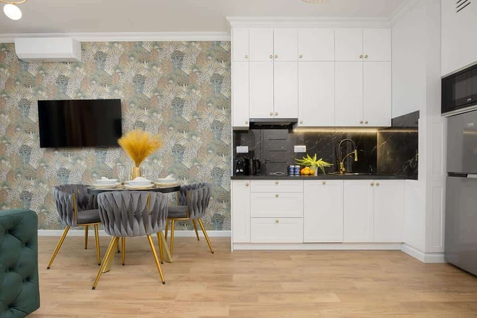 A modern kitchen with sleek white cabinetry, black countertops, and a built-in oven, blending functionality with style.

