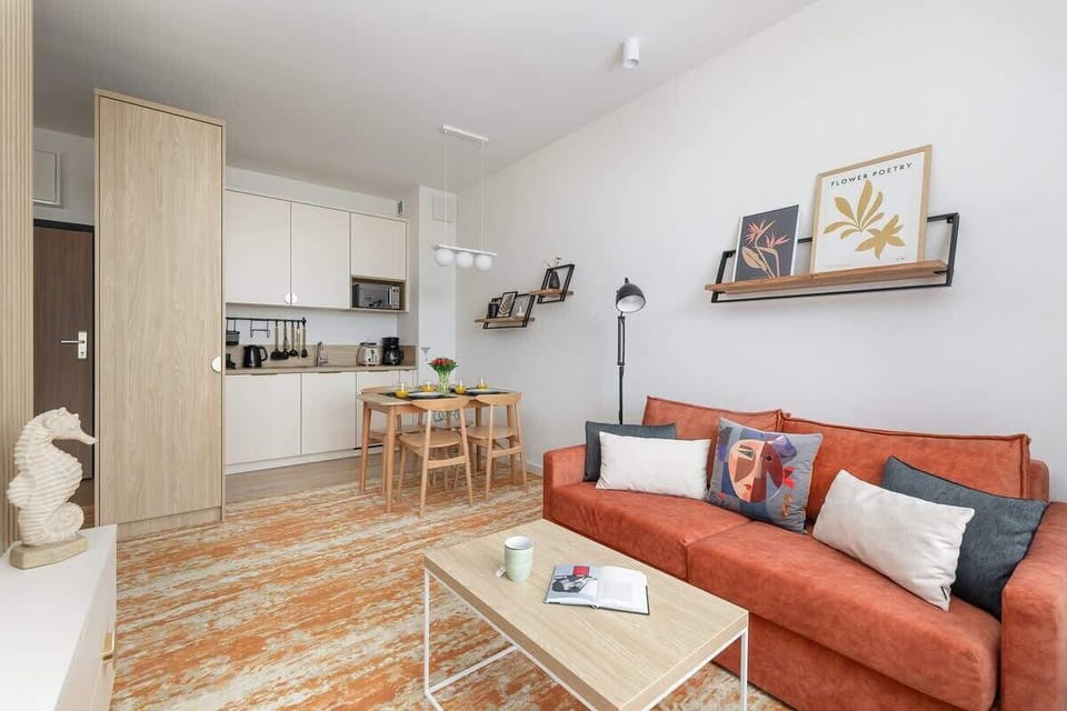 An open-plan living space with the kitchen visible in the background and a comfortable seating area in the foreground.