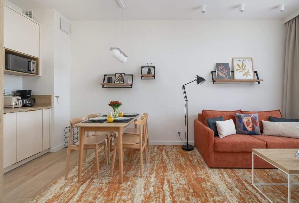 A combined kitchen and dining nook, featuring a wooden table set for four and white cabinetry overhead.