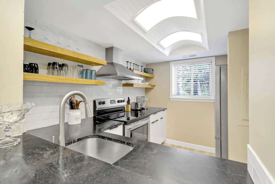 Cook with style in your modern kitchen featuring sleek countertops, open shelving, and abundant natural light from skylights above.