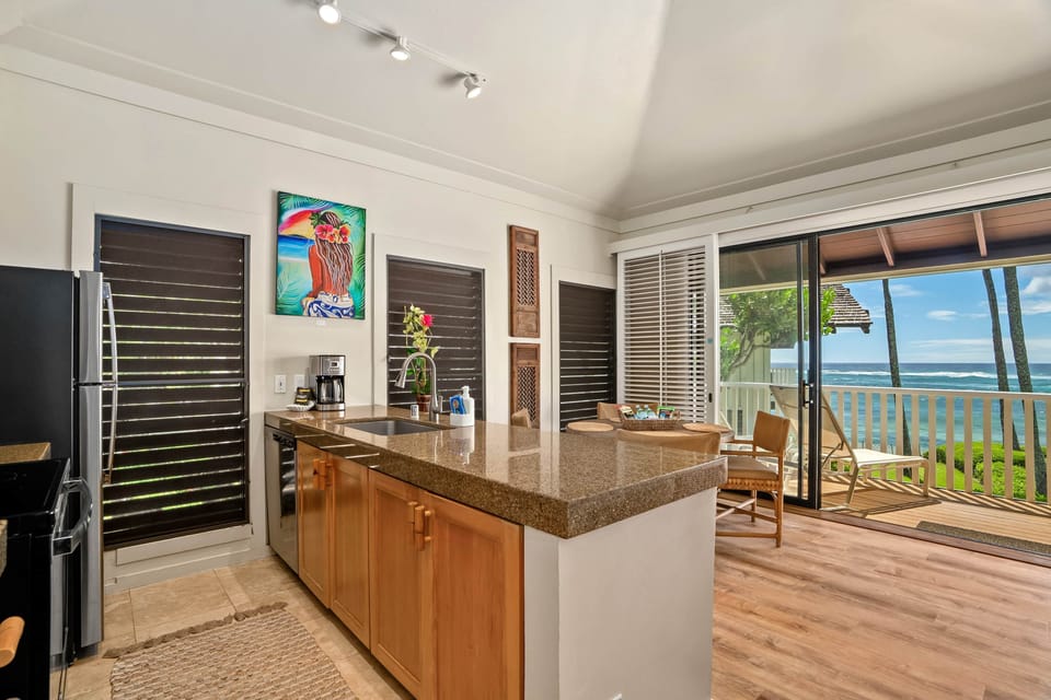 Granite island kitchen opens to lanai—cook with ocean views and breezy sun all day. Enjoy sunsets!