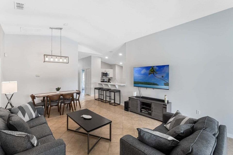 Relax in a spacious, modern lounge designed for family connection, featuring high ceilings, neutral tones, and a seamless flow from the kitchen to the dining area.