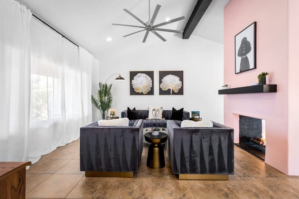 Living room - velvet channel-stitch sectional, lit pink fireplace accent wall, vaulted beam ceiling with oversized fan.