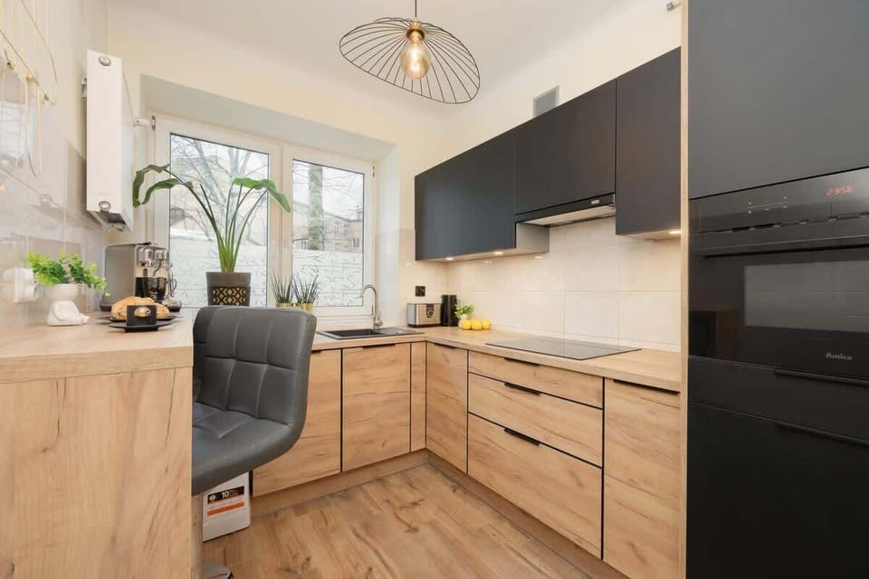 A modern kitchen with light wood cabinets and dark accents, featuring a spacious countertop and a range of high-quality appliances, perfect for cooking and entertaining.