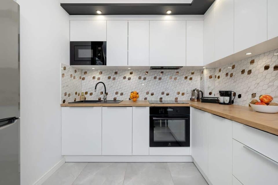 Stylish kitchen with white cabinets, built-in oven, and colorful backsplash tiles.