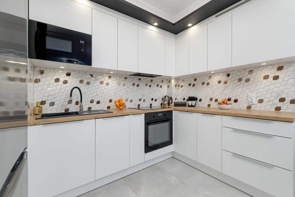 Stylish kitchen with white cabinets, built-in oven, and colorful backsplash tiles.