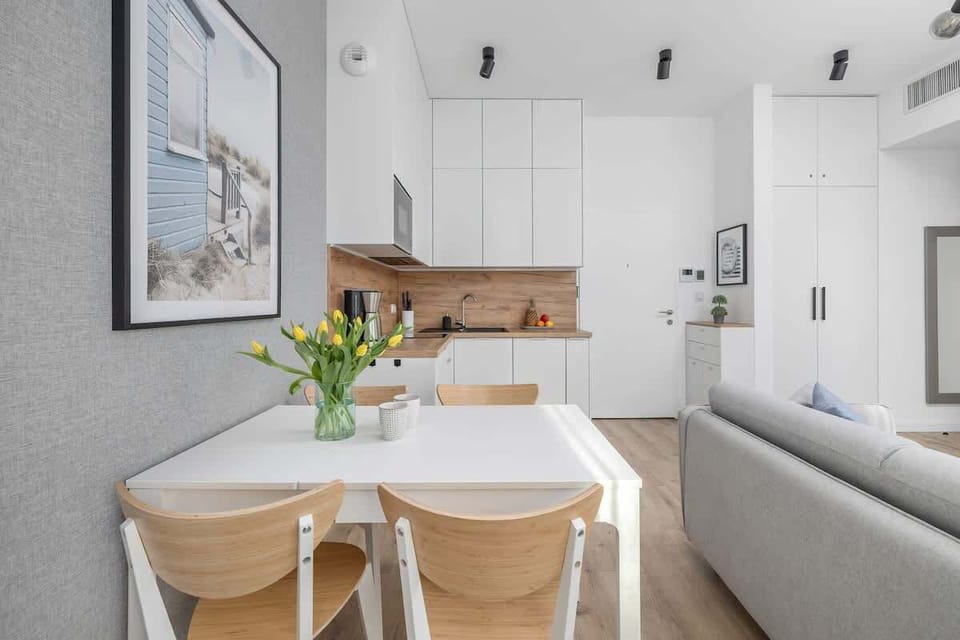 White minimalist kitchen with wooden countertops and modern appliances.