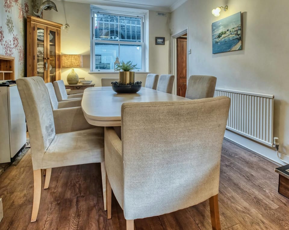 Dining room with table and eight chairs, small table with a lamp and corner storage cupboard