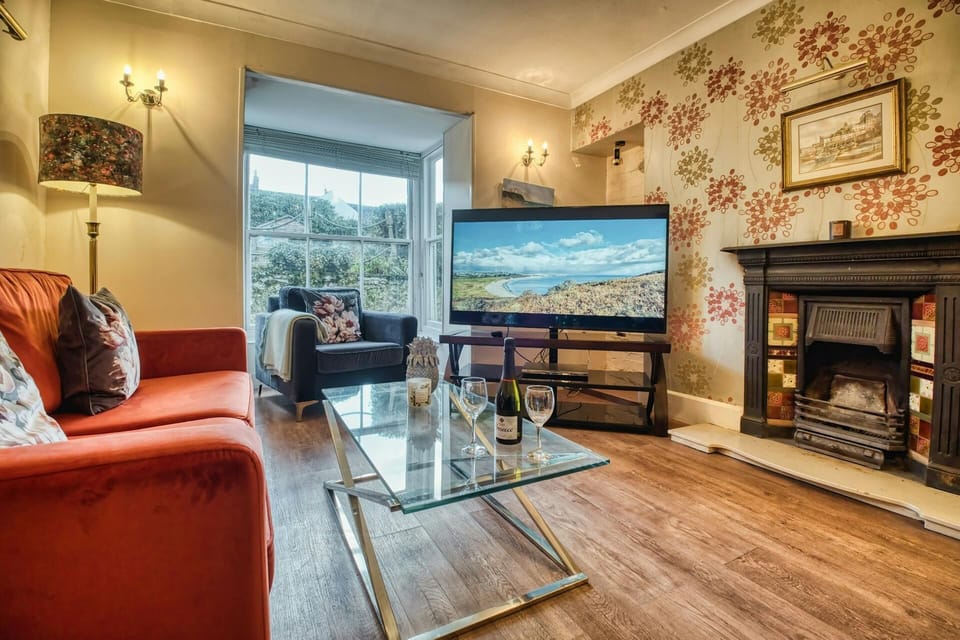 Sofa, armchair, large TV, standard lamp, ornamental fire place, and coffee table