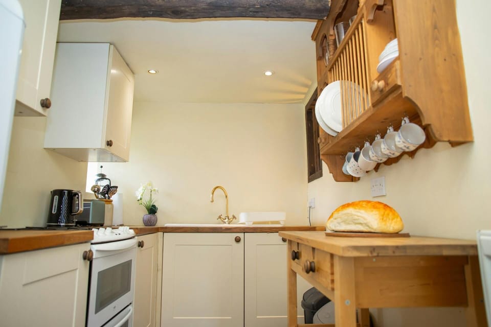 Kitchen with wall mounted plate rack, cooker, kettle, toaster and sink