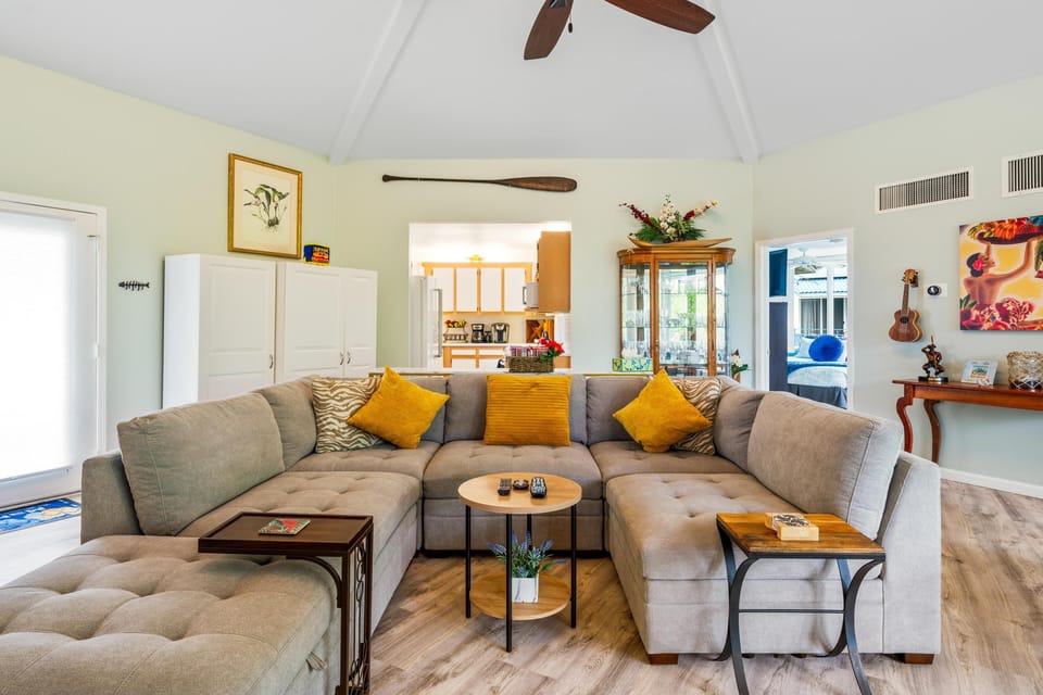 Spacious living area with Hawaiian décor, updated flooring, vaulted ceilings, and plenty of natural light — a relaxing space to unwind.