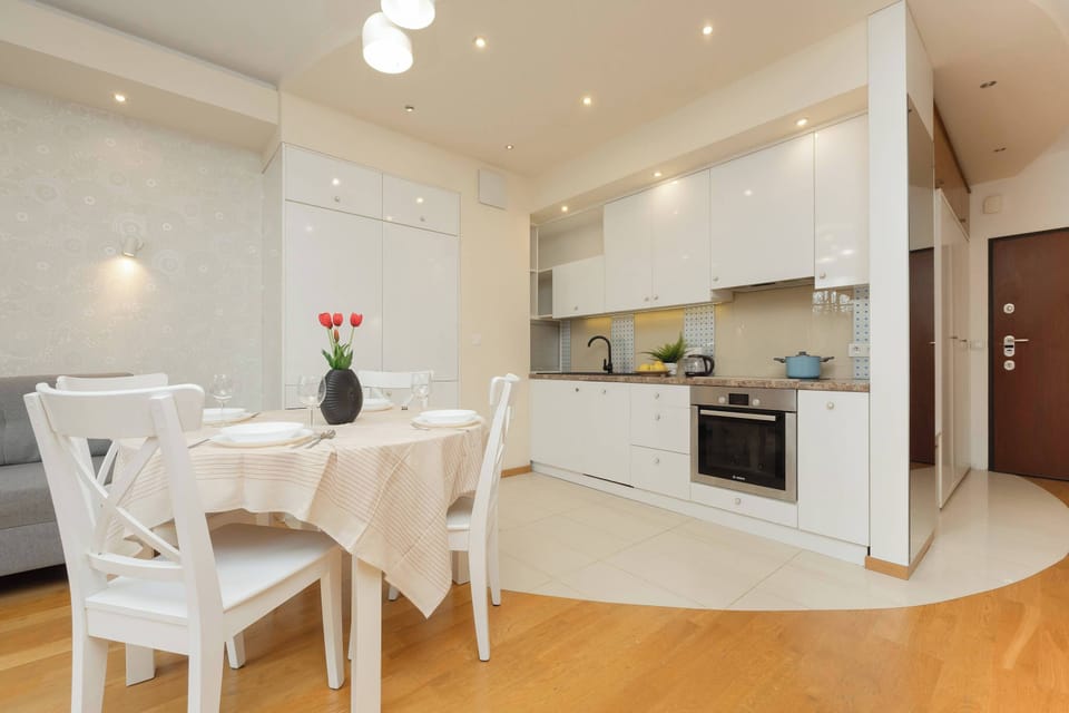 Modern white kitchen with built-in appliances and wooden flooring.