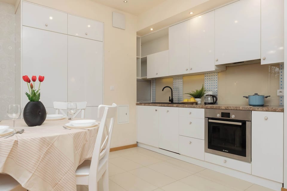 Modern white kitchen with built-in appliances and wooden flooring.