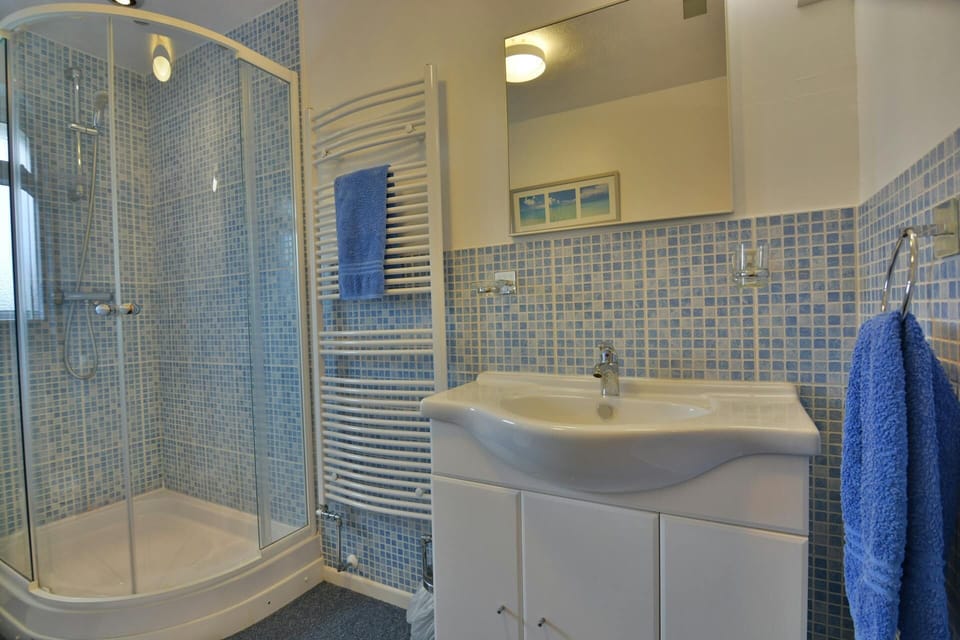 Bright family shower room with walk in shower, heated towel rail, wash basin unit with mirror above