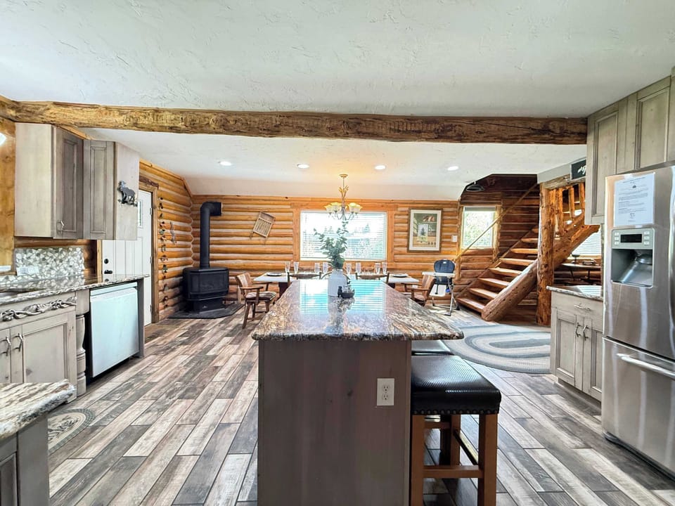 The beautifully designed kitchen blends rustic log charm with modern convenience, complete with high-end stainless steel appliances and smooth hardwood-style flooring.