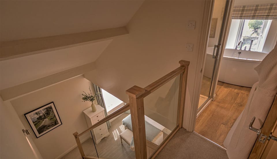 Luxury bathroom at Woodcroft Cottage featuring freestanding bath, skylight ceiling and modern fittings.