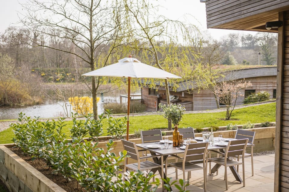 Private patio with outdoor seating and garden views towards lakes at Jules Lodge, Brompton Lakes.