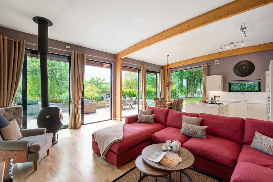 Open-plan living area with log burner and garden views in Jules lodge at Brompton Lakes.